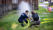 Feuerwehrmann, Elternteil plus Kind beim Spritzen mit Schlauch