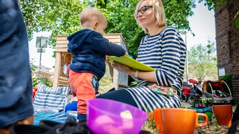 Eltern sitzen mit ihren Kindern auf dem TUD-Spielplatz Campuskiste