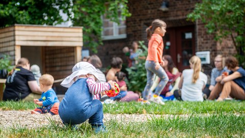 Kind spielend vor dem Campusbüro Uni mit Kind