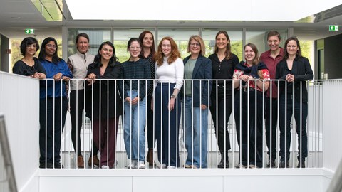 Ein Gruppenbild von 12 Frauen, die hinter einem weißen Geländer stehen.