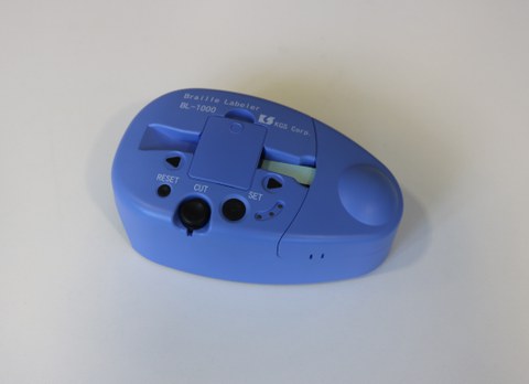The photo shows the Braille labeling device lying on the table.