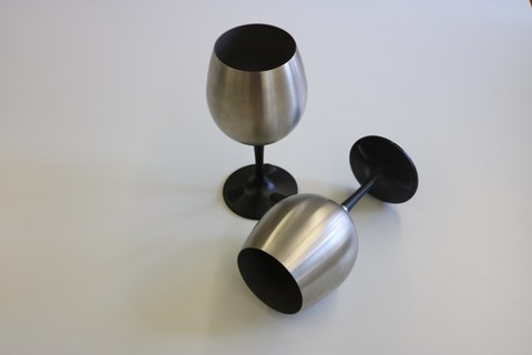 The photo shows the two stainless steel wine glasses, one vessel lies crosswise in front of the upright vessel.