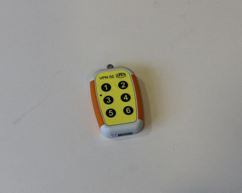 Photo shows the Apex command transmitter lying on the table, it looks like a small remote control with a yellow keypad on which the numbers 1 to 6 are listed, always two numbers in a row chronologically.
