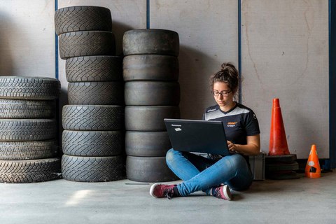 Frau sitz vor einem Reifenstapel mit einem Laptop in der Hand