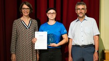 Three people are standing together and one person is holding an award.