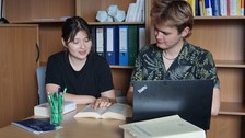 Auf dem Bild ist eine Frau und ein Mann zu sehen, die an einem Tisch sitzen  und gemeinsam in einen Gesetzestext schauen.