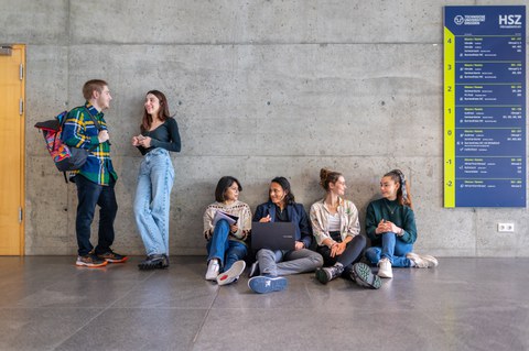 Fotos von 4 auf dem Boden sitzenden und 2 stehenden sich unterhaltende Studierenden in einem TUD-Gebäude