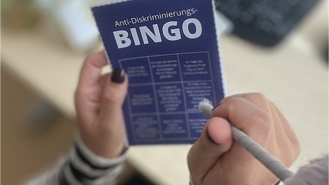 Ein Person hält das Anti-Diskriminierungs-Bingo in der Hand