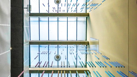 Foto nach oben auf die Kunstinstallation von Roland Fuhrmann mit bunten hängenden Röhren im Chemiebau.