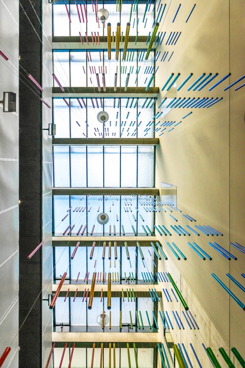 Foto nach oben auf die Kunstinstallation von Roland Fuhrmann mit bunten hängenden Röhren im Chemiebau.