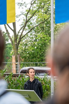 Person steht im Garten des Rektorats am Redner:innenpult