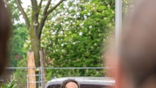 Person steht im Garten des Rektorats am Redner:innenpult