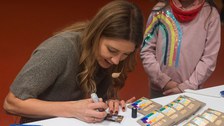 Jana Forkel unterschreibt Autogrammkarten. Neben ihr steht ein kleines Mödchen. 