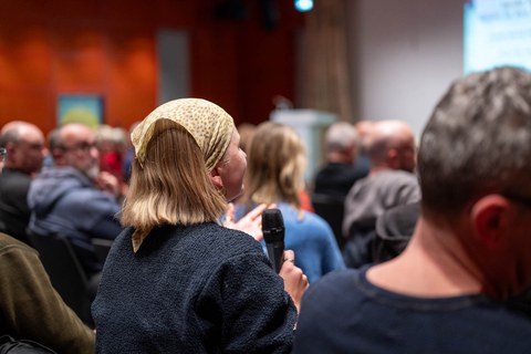 Eine junge Person aus dem Publikum spricht ins Mikrofon