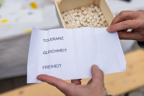 2 Hände halten einen Zettel in die Kamera, auf dem die Worte Toleranz, Gleichheit und Freiheit stehen. 