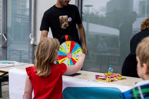 Ein kleines Mädchen mit rotem T-Shirt spielt an einem kleinen Glücksrad. 