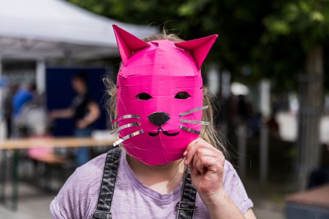 Ein Kind, das eine selbst gebastelte pinke Maske trägt.
