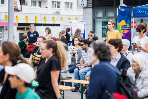 Personen sitzen auf Festzeltbänken.