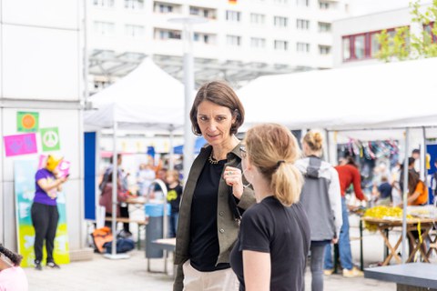3 Personen stehen zusammen und unterhalten sich. Eine der Personen trägt einen dunkelblauen Hoodie mit der Aufschrift Technische Universität Dresden.