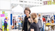 3 Personen stehen zusammen und unterhalten sich. Eine der Personen trägt einen dunkelblauen Hoodie mit der Aufschrift Technische Universität Dresden.