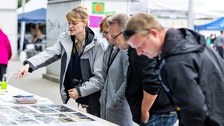 4 Personen stehen an einem Festzelttisch, auf dem Fotos liegen. 