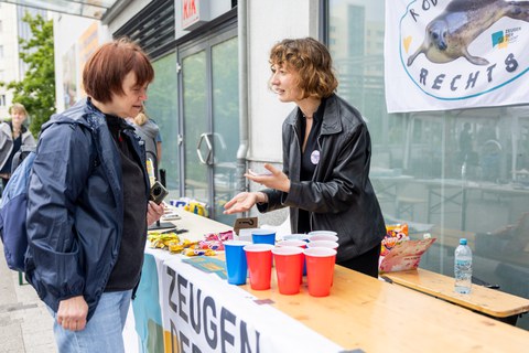 2 Personen stehen sich an einem Festzelttisch gegenüber und unterhalten sich. 