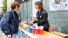 2 Personen stehen sich an einem Festzelttisch gegenüber und unterhalten sich. 