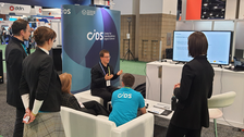 Foto während eines Sofa-Talks am gemeinsamen Messestand von ZIH und ScaDS.AI auf der SC23 in Denver. Vortragender und 5 Personen vor einem Monitor.