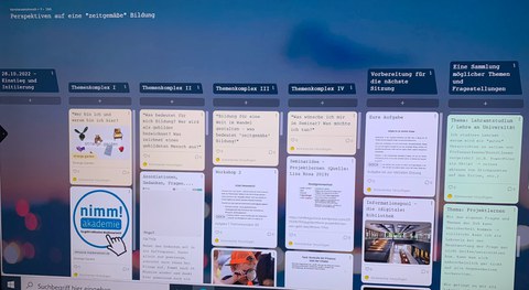 Das Foto zeigt einen Computerbildschirm mit dem Programm "Padlet" offen. Links oben steht die Überschrift "Perspektiven auf eine zeitgemäße" Bildung". Der Bildschirm ist in 6 Spalten unterteilt, jede Spalte hat eine Überschrift, darunter sind in Rechtecken Beiträge zu sehen. Im Hintergrund des Padlets ist ein verschwommenes Bild in Blautönen zu sehen.