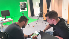 Zwei Menschen arbeitend vor Computern, in einem Raum mit Greenscreen 