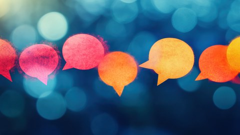 Colorful, glowing speech bubbles against a blurred blue background symbolize communication and exchange.