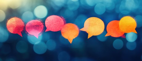 Colorful, glowing speech bubbles against a blurred blue background symbolize communication and exchange.