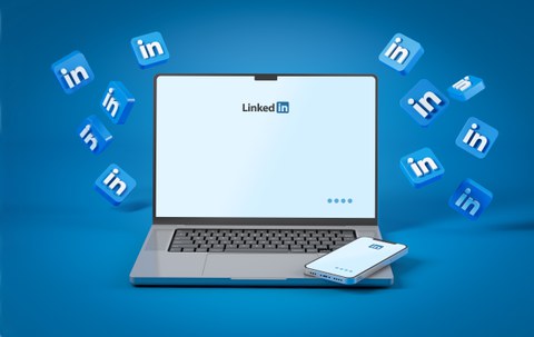 A laptop with a smartphone next to it, both displaying the LinkedIn logo on their screens. Several blue LinkedIn icons float around the device against a blue background.