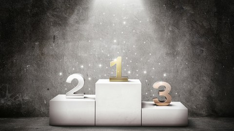 Die Darstellung zeigt ein Siegerpodest. Darauf stehen die Zahlen 1, 2 und 3. 