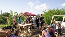 Young people sit and stand outside in a field and work.
