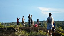 Young people stand on a hill and take photos of the surroundings.