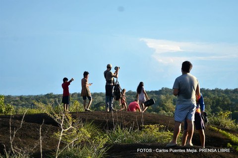 Young people stand on a hill and take photos of the surroundings.
