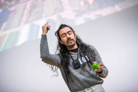 Gustavo Rosales präsentiert seinen Science Slam. In der hand hält er eine grüne Paprika.