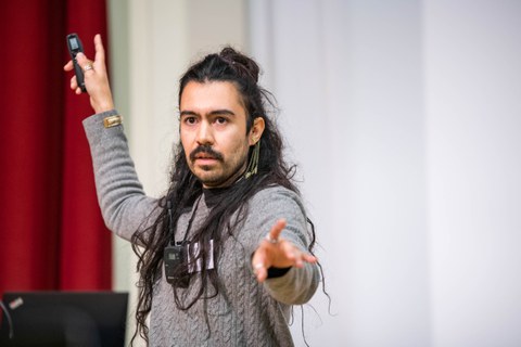 Gustavo Rosales präsentiert seinen Science Slam und zeigt in Richtung Kamera. 