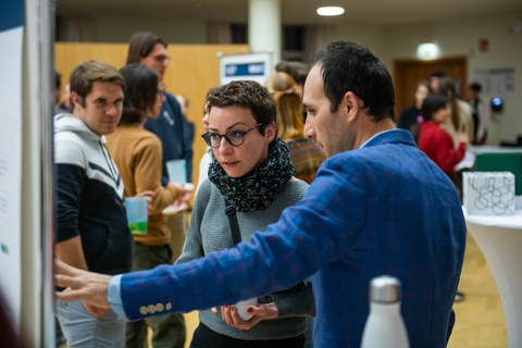 Hiva Osmani erklärt einer Besucherin sein Poster.