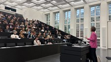 Die Prorektorin spricht in einem großen, hellen Hörsaal zu zahlreichen Studierenden, die aufmerksam zuhören.