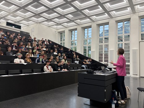 Die Prorektorin spricht in einem großen, hellen Hörsaal zu zahlreichen Studierenden, die aufmerksam zuhören.