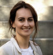 Frau mit dunklen Haaren lächelt in die Kamera