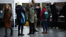 Viele Menschen unterhalten sich vor einem Zelt.