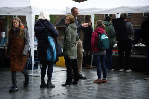 Viele Menschen unterhalten sich vor einem Zelt.