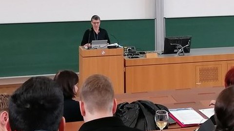 Prof. Hoffkamp steht im Hörsaal und begrüßt die Teilnehmenden