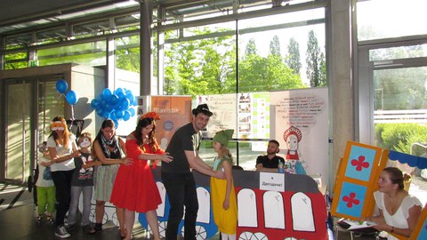 Foto von 7 Personen, die eine Menschenkette bilden. Daneben sitzen zwei Personen, die ihnen zuschauen.