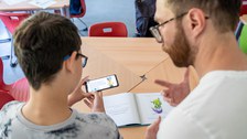 Junge und Mann gucken gemeinsam auf ein Smartphone