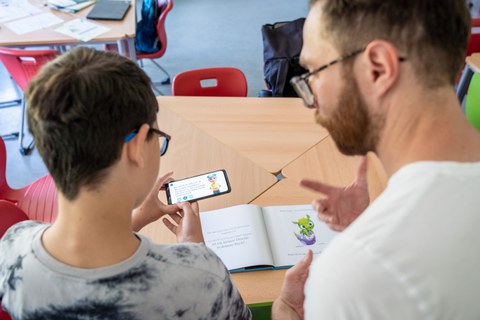 Junge und Mann gucken gemeinsam auf ein Smartphone
