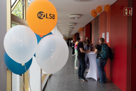 Foto eines Ganges mit Menschen, im Vordergrund Luftballons zum ZLSB Jubiläum.